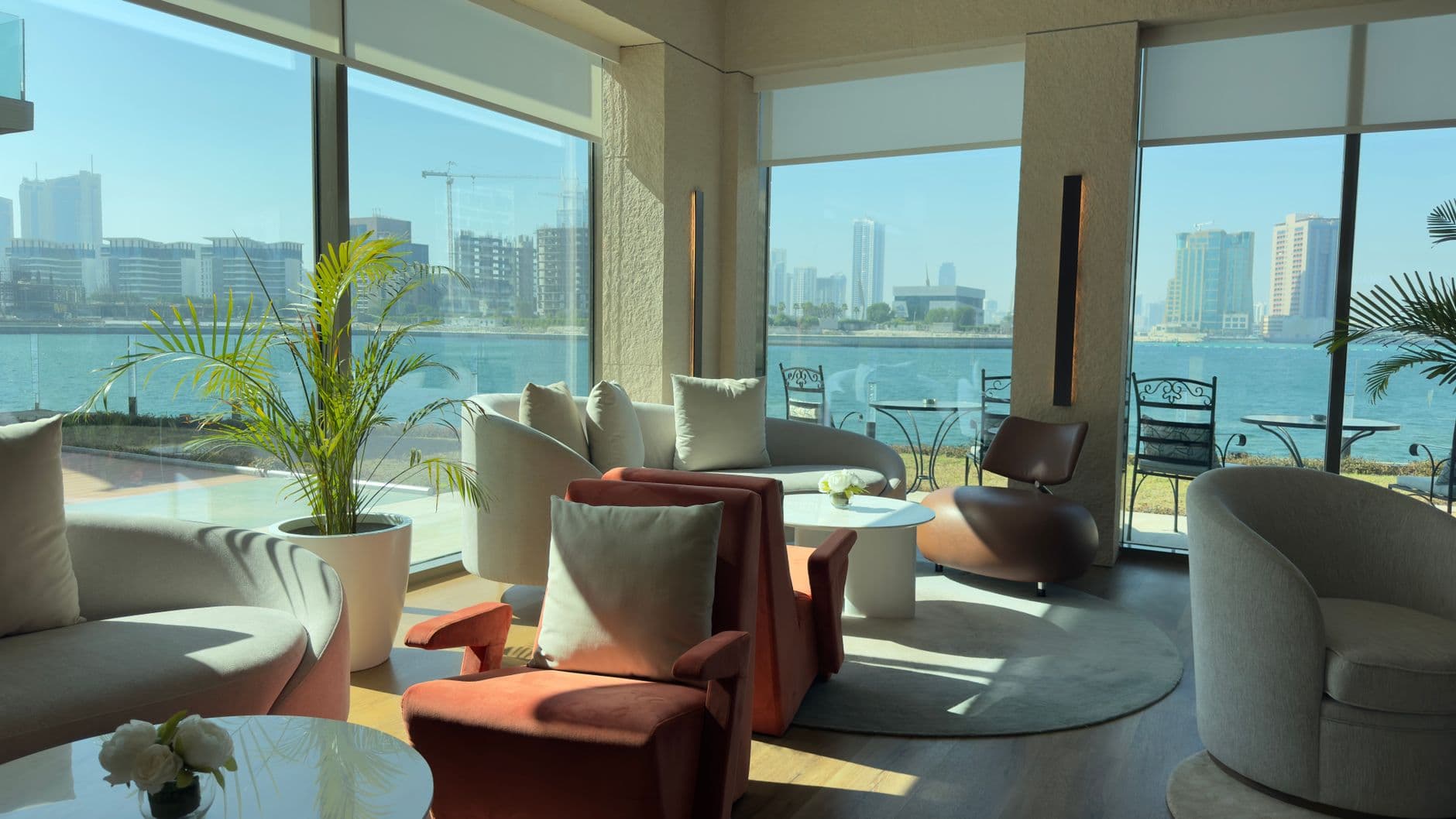 Spacious waterfront lounge featuring modern decor and scenic city skyline views through large windows.