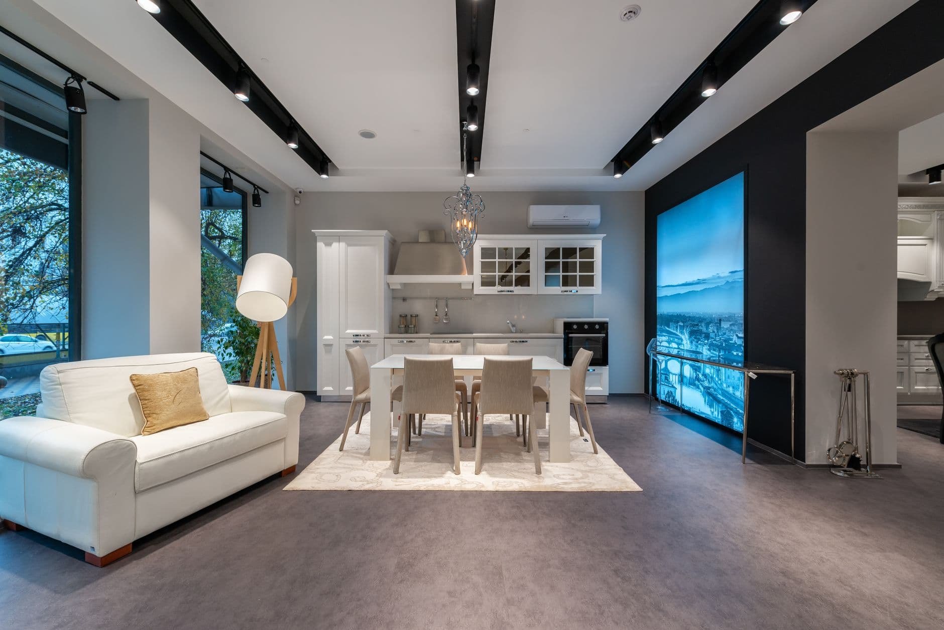 Elegant kitchen with white cupboards and dining table placed near cozy armchair placed in modern spacious furniture store