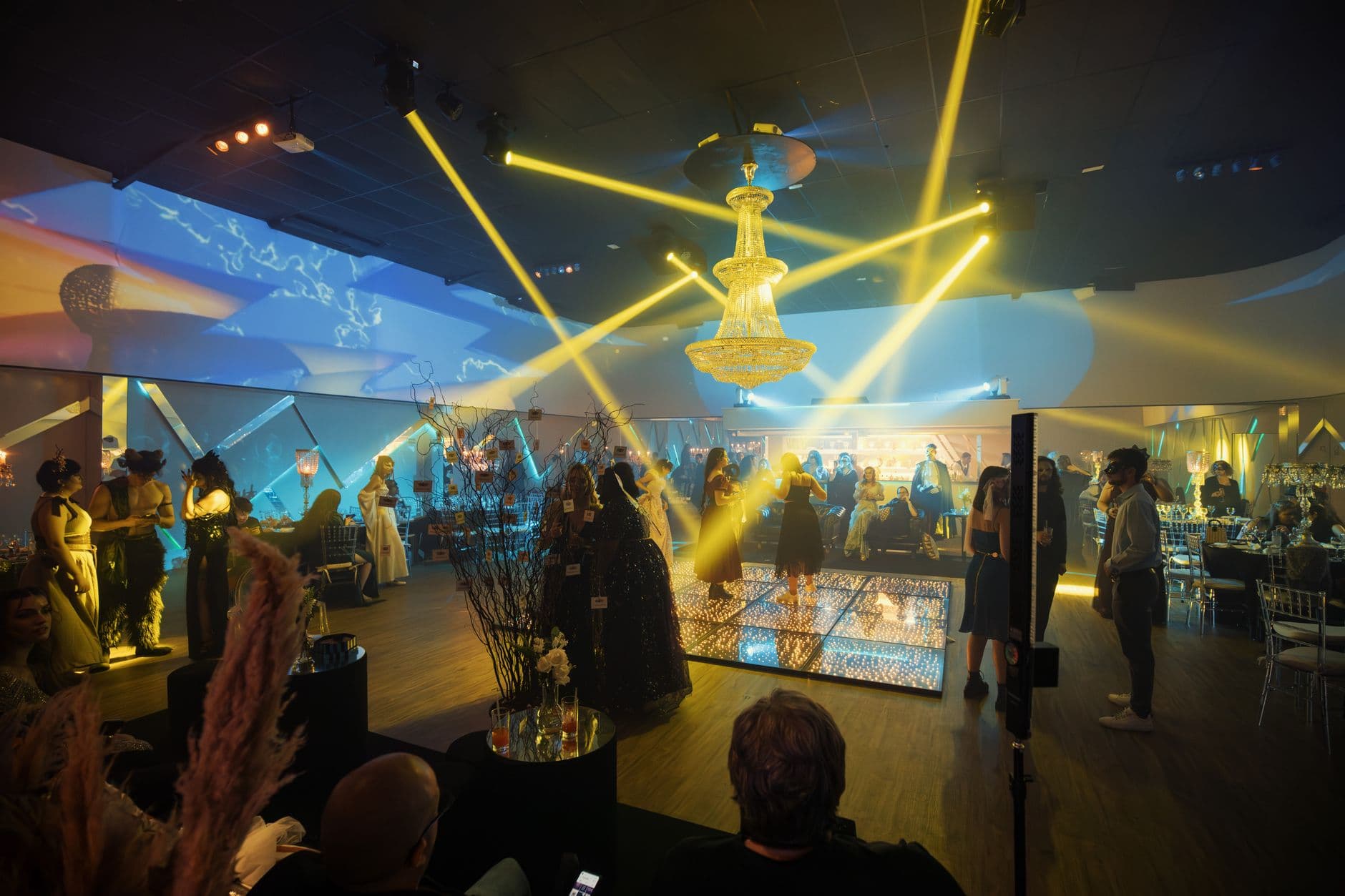 A stylish party scene with guests and a dance floor under dramatic lighting.