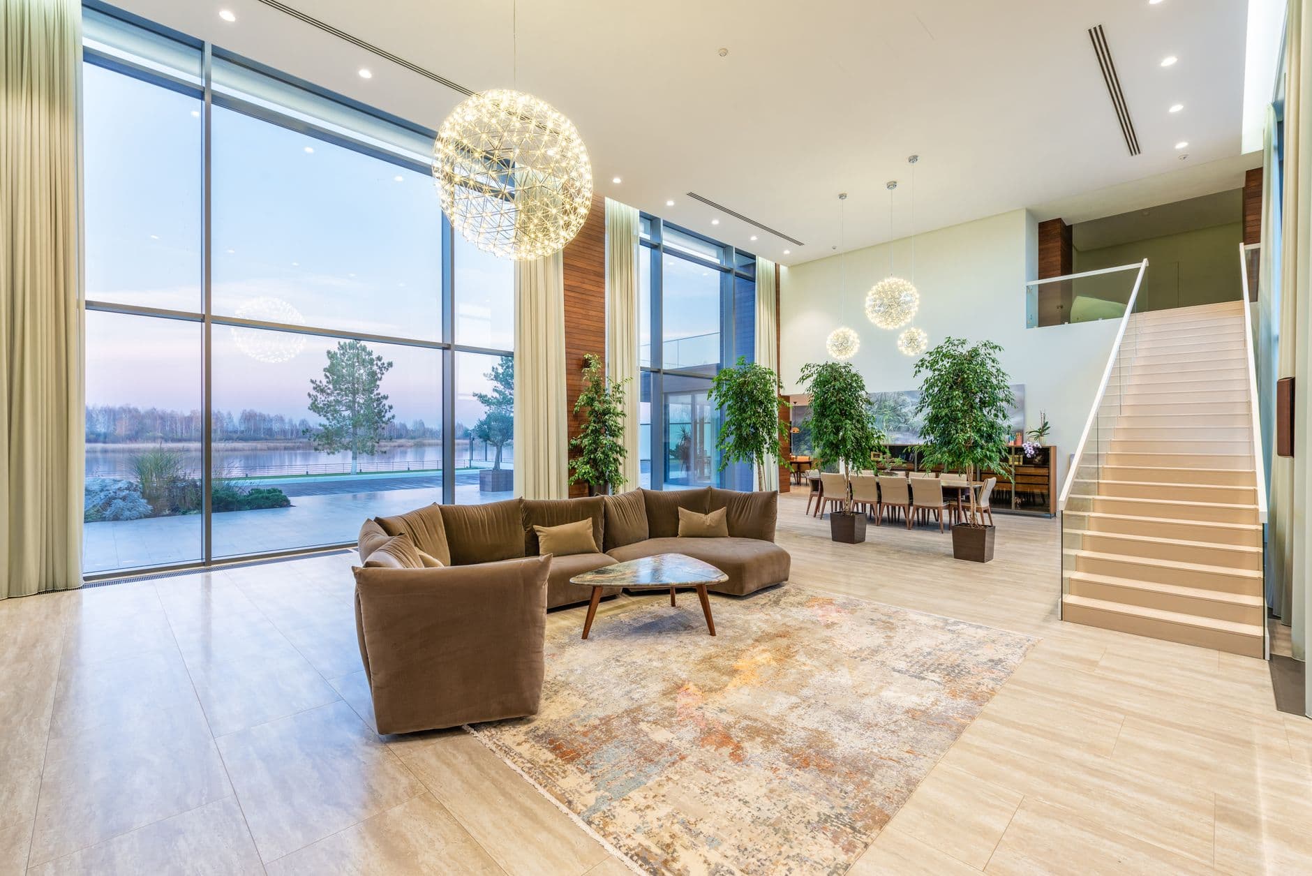 Interior of modern loft lobby with comfortable sofa near staircase and glass transparent wall with scenery view